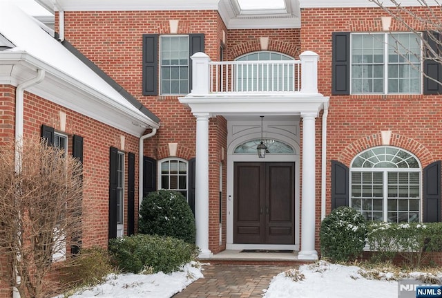 snow covered property entrance with a balcony