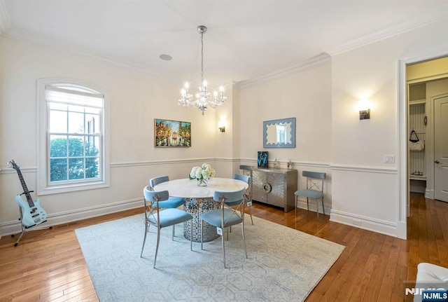 dining room with crown molding, hardwood / wood-style floors, and an inviting chandelier