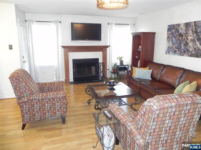 living area with a fireplace with flush hearth, wood finished floors, and a healthy amount of sunlight