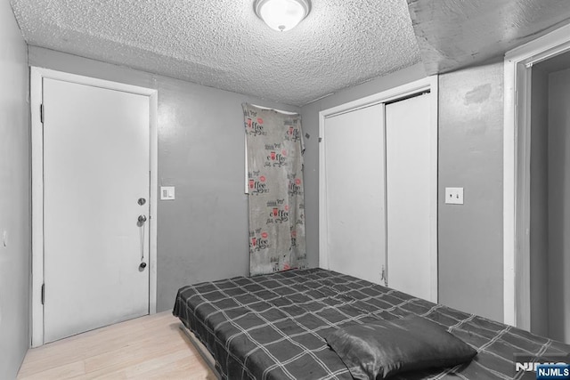 bedroom featuring a textured ceiling, light hardwood / wood-style floors, and a closet