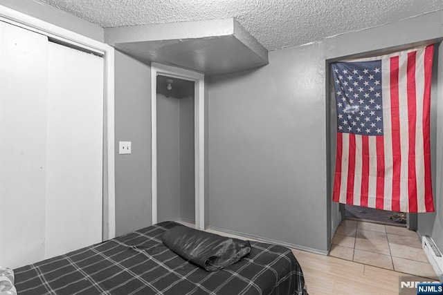 bedroom with a closet, wood-type flooring, and a textured ceiling