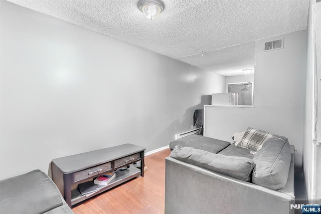 living room with hardwood / wood-style flooring, a baseboard radiator, and a textured ceiling