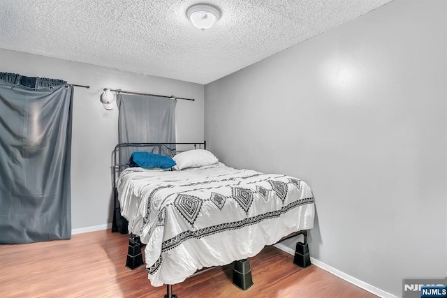 bedroom with wood-type flooring and a textured ceiling