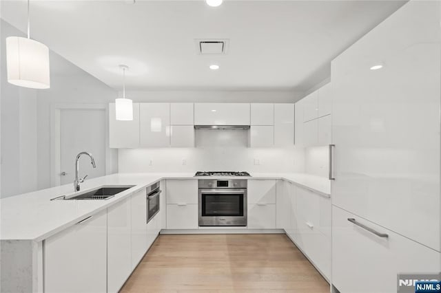 kitchen with white cabinetry, sink, oven, and decorative light fixtures