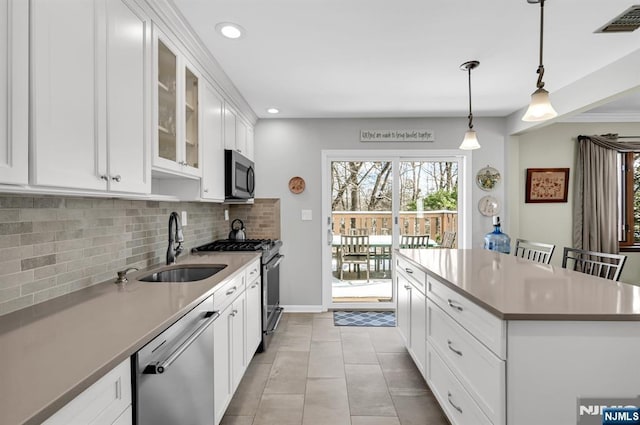 kitchen featuring sink, decorative light fixtures, appliances with stainless steel finishes, a kitchen breakfast bar, and white cabinets