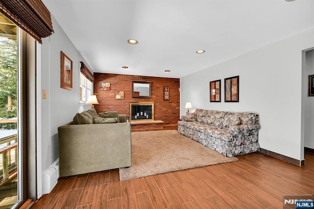 living room with hardwood / wood-style flooring, a brick fireplace, and a baseboard heating unit