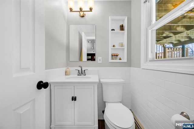 bathroom featuring vanity, toilet, and tile walls