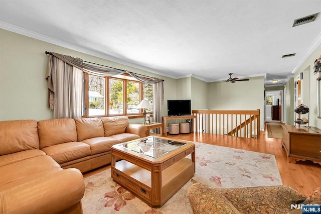 living room with ceiling fan, ornamental molding, and light hardwood / wood-style flooring