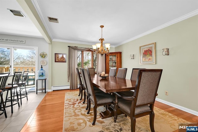 dining space featuring an inviting chandelier, a baseboard heating unit, ornamental molding, and light wood-type flooring