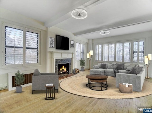 living room with a high end fireplace, beamed ceiling, and light wood-type flooring