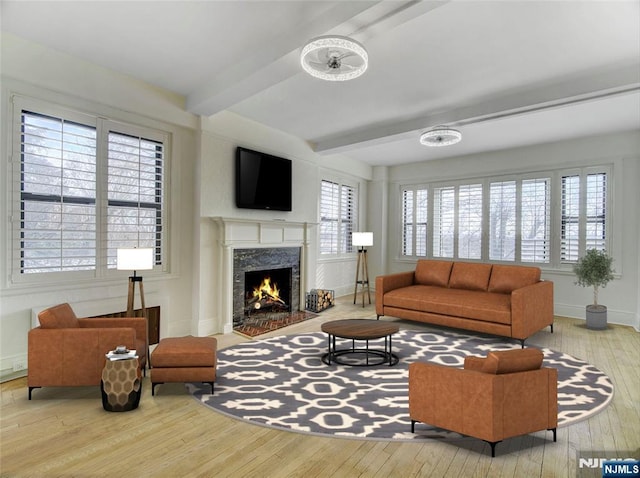 living room featuring a high end fireplace, beam ceiling, and light wood-type flooring