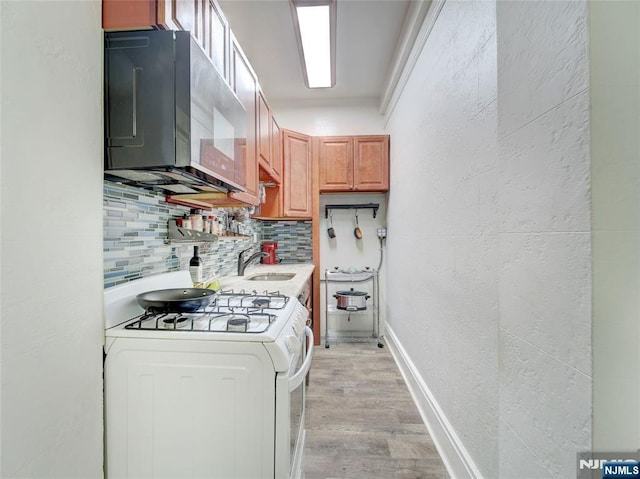 kitchen with white range with gas cooktop, sink, decorative backsplash, and light wood-type flooring