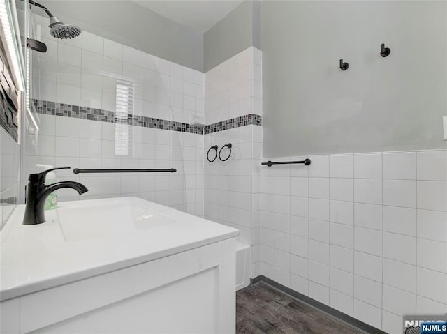 bathroom with sink, hardwood / wood-style floors, and tile walls