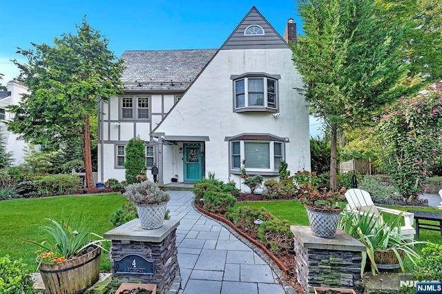 tudor home with a front lawn and a patio