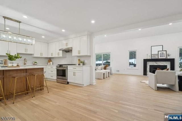 kitchen featuring hanging light fixtures, stainless steel stove, a breakfast bar area, and white cabinets