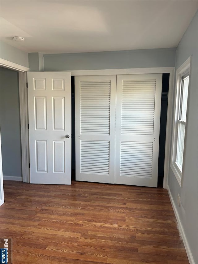 unfurnished bedroom with dark wood-type flooring and a closet