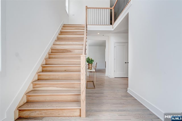 stairs with hardwood / wood-style flooring and a high ceiling