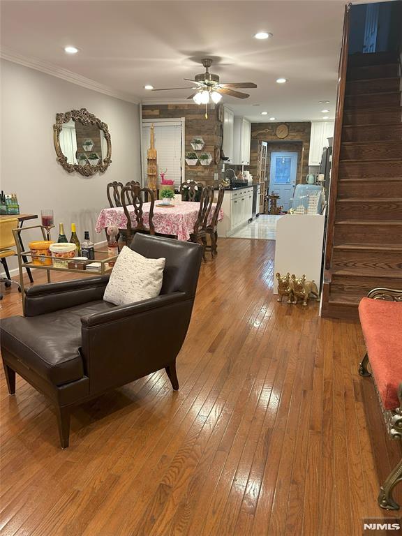 living room featuring hardwood / wood-style flooring, crown molding, and ceiling fan