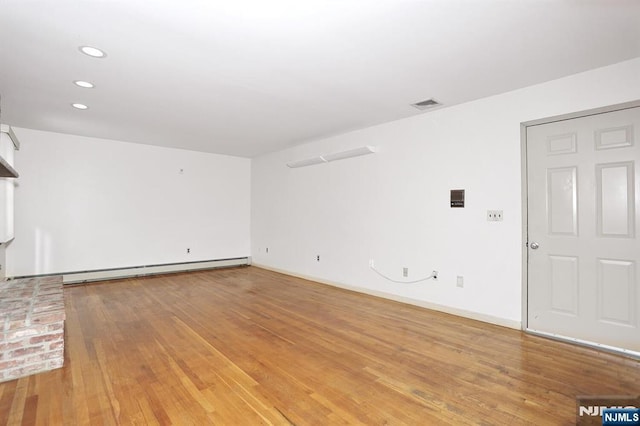 unfurnished living room featuring hardwood / wood-style floors and baseboard heating