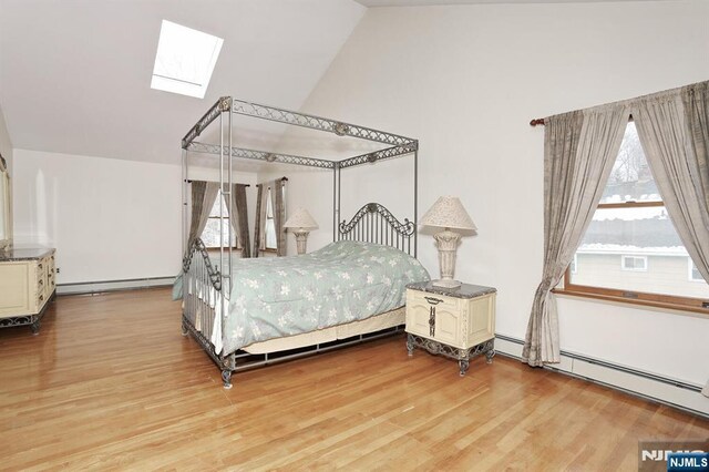 bedroom featuring multiple windows, lofted ceiling with skylight, hardwood / wood-style flooring, and baseboard heating