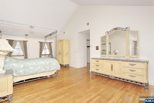 bedroom featuring high vaulted ceiling and light hardwood / wood-style flooring