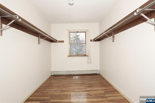 spacious closet with wood-type flooring and baseboard heating