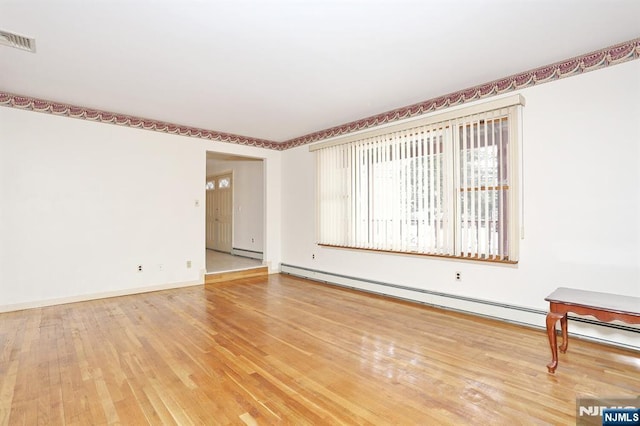 spare room featuring hardwood / wood-style flooring and baseboard heating