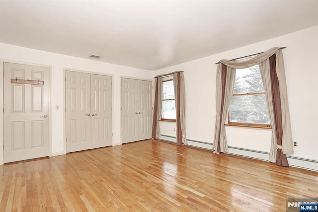 unfurnished bedroom featuring light hardwood / wood-style floors and two closets