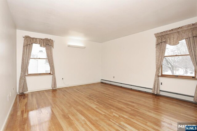 unfurnished room featuring baseboard heating and wood-type flooring