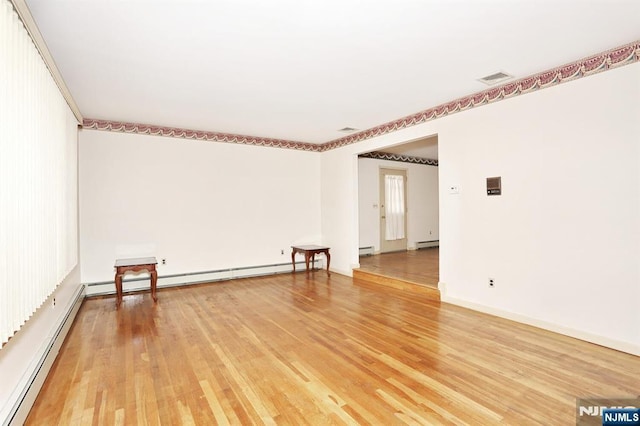 unfurnished room featuring baseboard heating and wood-type flooring