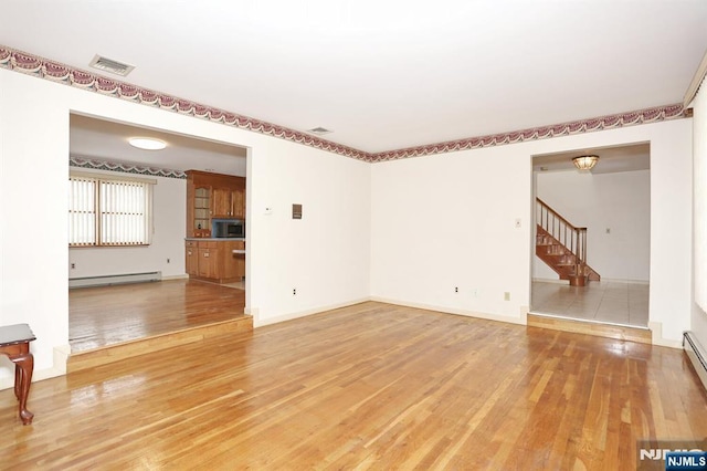 unfurnished living room with a baseboard radiator and hardwood / wood-style floors