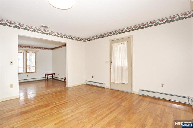 empty room with hardwood / wood-style flooring and a baseboard heating unit