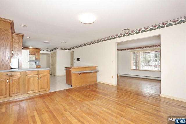 kitchen with a baseboard radiator, stove, a breakfast bar, and light wood-type flooring