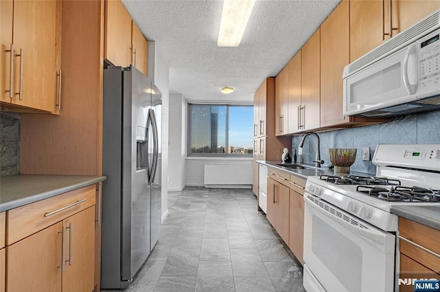 kitchen with tasteful backsplash, white appliances, light countertops, and a sink