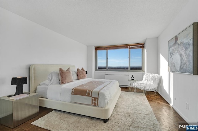 bedroom featuring a textured ceiling, baseboards, and radiator