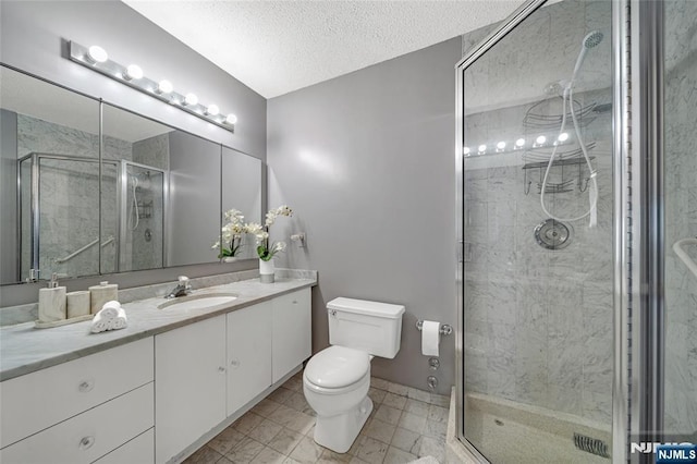 bathroom with a stall shower, toilet, vanity, and a textured ceiling