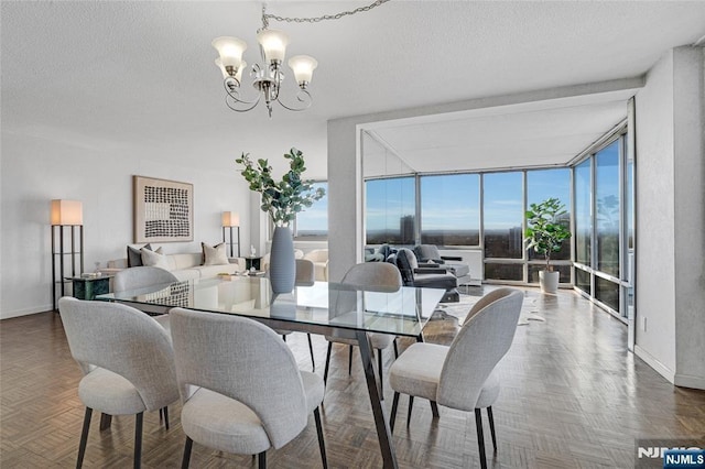 dining room featuring a wall of windows, a notable chandelier, a textured ceiling, and baseboards