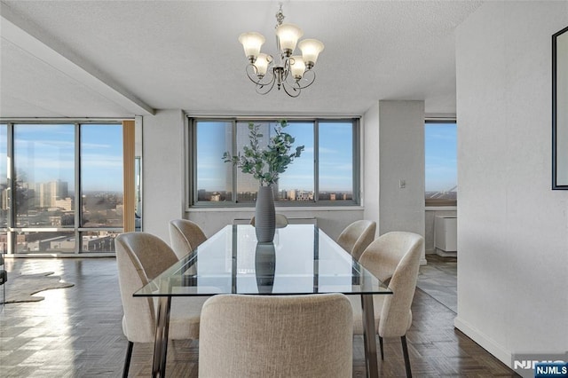 dining room with a chandelier, a textured ceiling, a city view, baseboards, and floor to ceiling windows