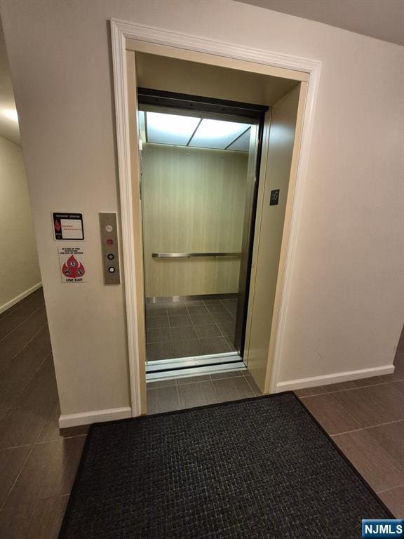 interior space with dark tile patterned flooring and elevator