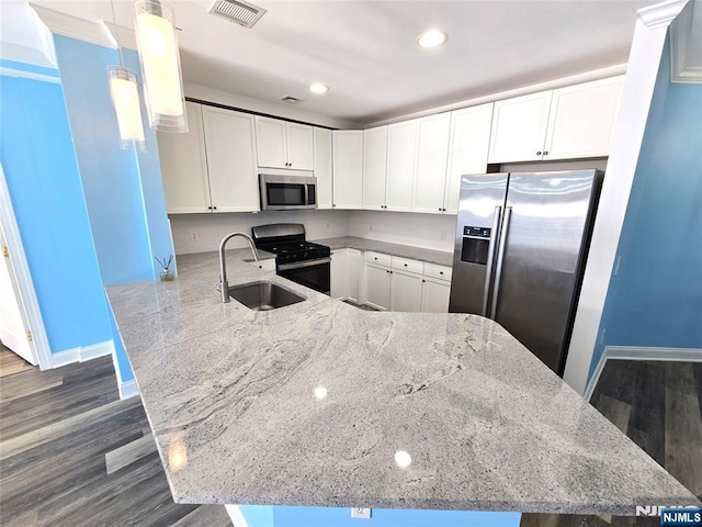 kitchen with decorative light fixtures, kitchen peninsula, white cabinets, and appliances with stainless steel finishes