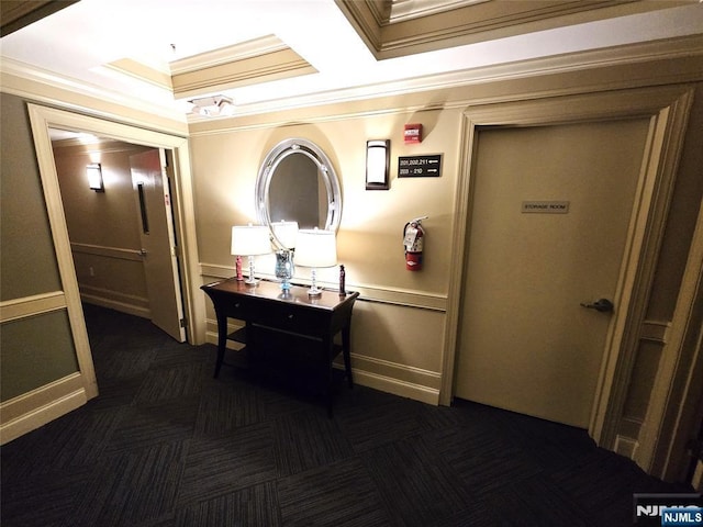 hallway featuring ornamental molding and dark carpet