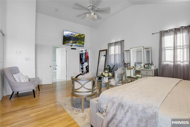 bedroom with a walk in closet, high vaulted ceiling, a closet, and light wood-type flooring