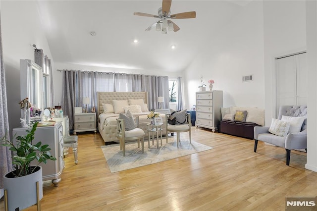 bedroom with light wood-type flooring, high vaulted ceiling, and a closet