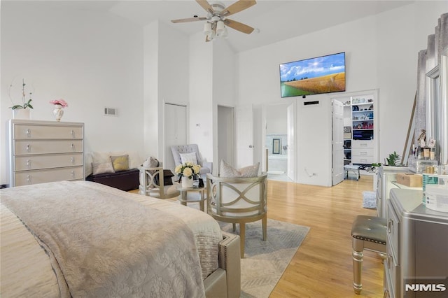 bedroom with high vaulted ceiling, ensuite bath, and light hardwood / wood-style floors