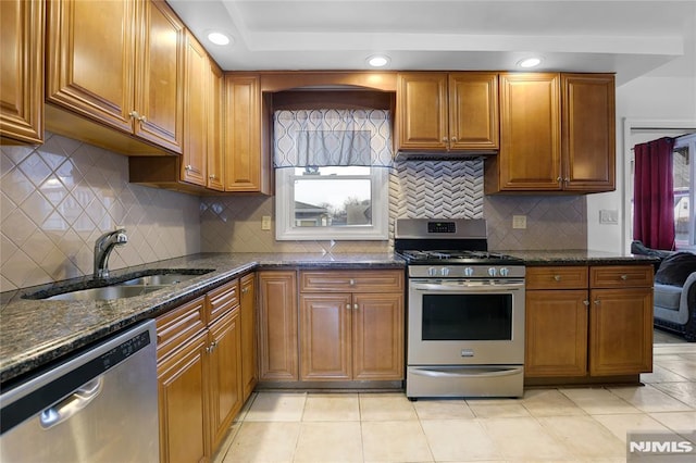 kitchen with sink, dark stone countertops, backsplash, light tile patterned floors, and stainless steel appliances