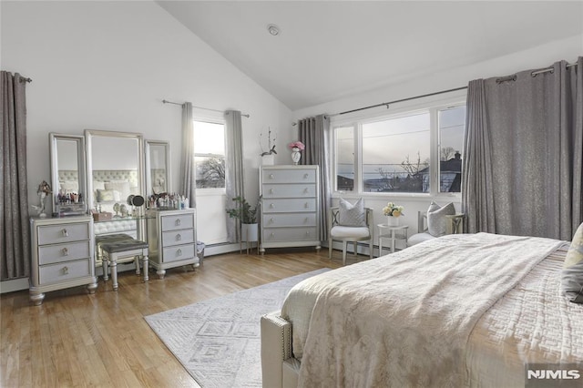 bedroom featuring baseboard heating, high vaulted ceiling, and light wood-type flooring