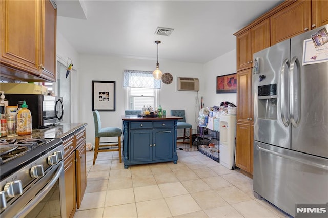 kitchen featuring pendant lighting, appliances with stainless steel finishes, a wall unit AC, and light tile patterned floors