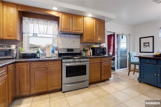 kitchen featuring appliances with stainless steel finishes, dark stone counters, and decorative backsplash