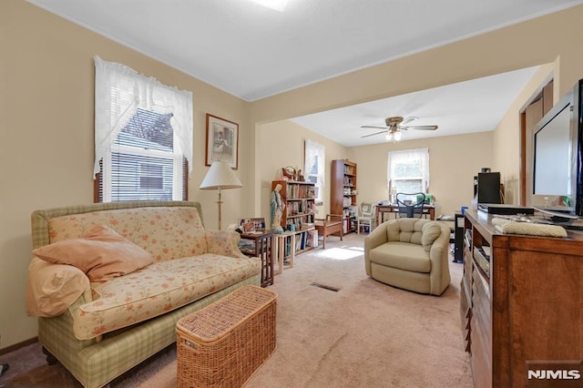 living area with light carpet and ceiling fan