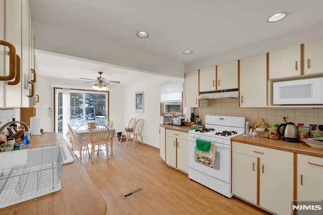 kitchen featuring tasteful backsplash, under cabinet range hood, light wood-type flooring, recessed lighting, and white appliances